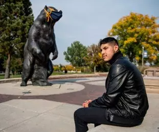 Photo of Noah Cordova at the UNC campus with a Bear statue in background